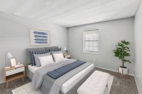 Olathe apartment for rent - A bedroom with a bed, nightstand, and a plant.