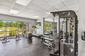 Olathe apartment for rent - A gym with a variety of equipment including a weight bench, a leg press machine, and a cable machine.