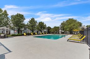 Kansas City apartment for rent - A large outdoor swimming pool surrounded by yellow sun loungers.