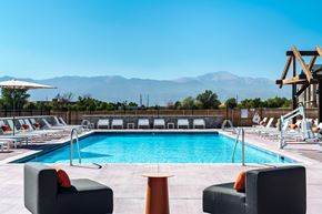 Colorado Springs apartment for rent - A pool area with lounge chairs and mountains in the background.