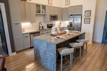 Designer kitchen packages with two-toned cabinets, stainless-steel appliances, tile backsplash, granite countertops, waterfall island*, and black hardware