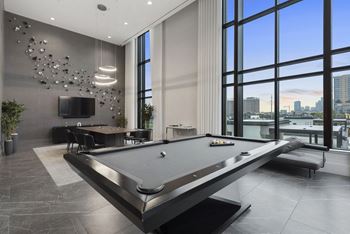 A billiards table in a game room with a view of the city