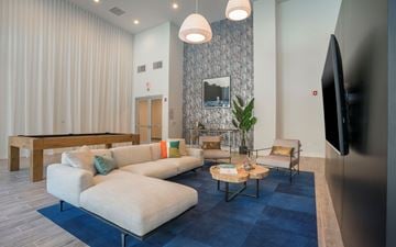 San Diego apartment for rent - A living room with a blue rug and a television on the wall.