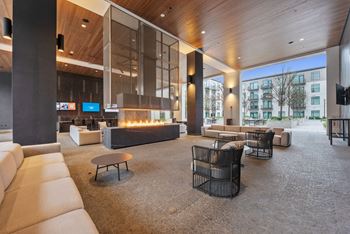 The lobby of a hotel with couches and chairs and a fireplace