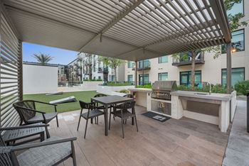 A patio with a table and chairs and a grill