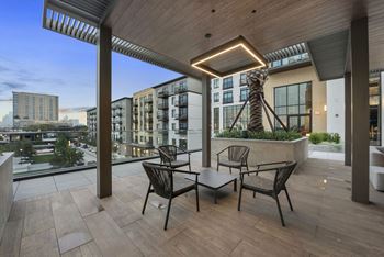 A terrace with a table and chairs and a view of the city