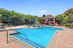 Atlanta apartment for rent - A large swimming pool surrounded by a brick patio and lounge chairs.