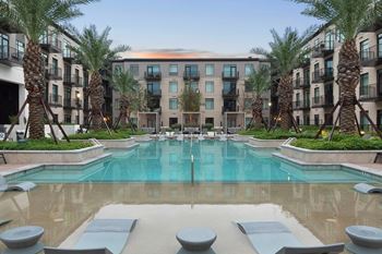 A swimming pool with palm trees in front of an apartment building