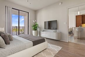 Doral apartment for rent - A bedroom with a large bed, a television, and a balcony with a view of the outdoors.