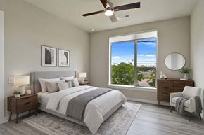Austin apartment for rent - A bedroom with a large bed, a window with a view, and a ceiling fan.
