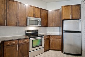 Dallas apartment for rent - Kitchen with wooden cabinets and appliances and a stainless steel refrigerator at The Monterey by Windsor, Dallas, Texas