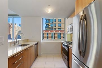 New York apartment for rent - A kitchen with a stainless steel refrigerator and wooden cabinets.