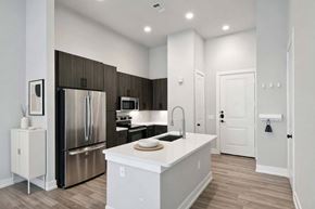 Austin apartment for rent - A modern kitchen with a stainless steel refrigerator and a white island.