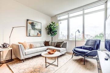 Chicago apartment for rent - A living room with a grey couch, a blue chair, and a painting on the wall.