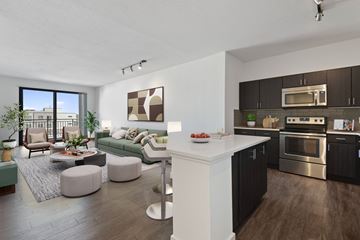 Denver apartment for rent - A modern kitchen with a breakfast bar and a living room with a couch and a coffee table.