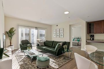 Atlanta apartment for rent - A living room with a green velvet sofa and a glass coffee table.