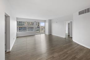 Austin apartment for rent - A spacious room with wooden flooring and a view of a building through the windows.