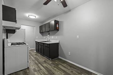 Ypsilanti apartment for rent - A kitchen with a white stove top oven and black cabinets.