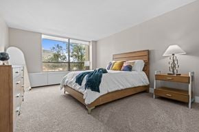 Southfield apartment for rent - A bedroom with a large bed and a window overlooking a cityscape.