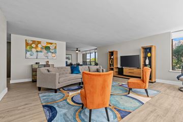 Southfield apartment for rent - A living room with a grey couch, orange chairs and a painting on the wall.
