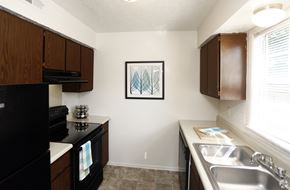 Indianapolis apartment for rent - A kitchen with a black refrigerator, a white oven, a white sink and brown cabinets.