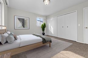 Southfield apartment for rent - A bedroom with a bed, a plant, and a framed picture on the wall.