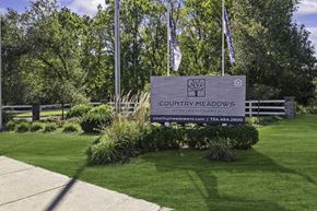 Ypsilanti apartment for rent - A sign for Country Meadows Community Apartments stands in a green field.