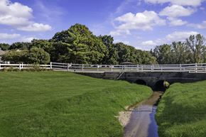 Ypsilanti apartment for rent - A bridge over a stream in a grassy field.