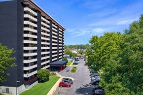 Memphis apartment for rent - A parking lot in front of a tall building with a red car in the foreground.