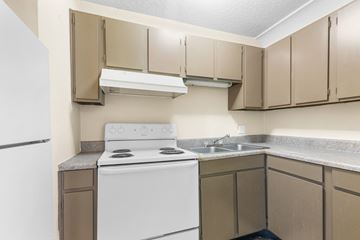 Memphis apartment for rent - A white stove and sink in a kitchen with beige cabinets.