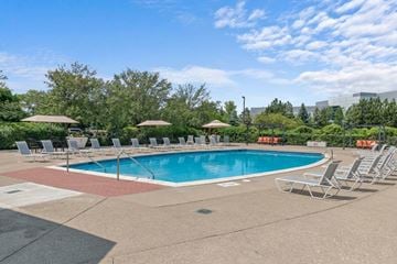 Southfield apartment for rent - A large outdoor swimming pool surrounded by lounge chairs and umbrellas.