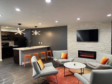 Indianapolis apartment for rent - A modern living room with grey chairs and a fireplace.