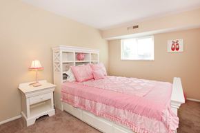 Cuyahoga Falls apartment for rent - A pink bed with a white nightstand and lamp in a bedroom.