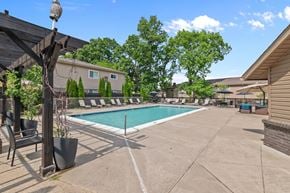 South Lyon apartment for rent - A pool area with a patio and a few chairs.