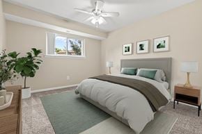 South Lyon apartment for rent - A bedroom with a large bed, a ceiling fan, and a potted plant.