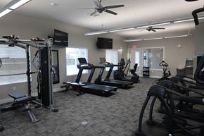 North Platte apartment for rent - A gym with a variety of equipment including treadmills, weights, and a television.
