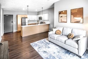 Lincoln apartment for rent - A modern living room with a white couch and a kitchen area in the background.
