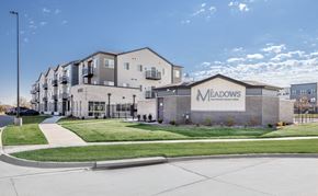 Lincoln apartment for rent - The Meadows apartment complex is a modern building with a spacious front lawn.