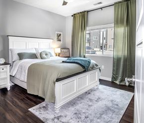 Lincoln apartment for rent - A bedroom with a large bed and a window with green curtains.