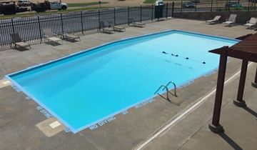 Topeka apartment for rent - A rectangular pool with a blue tinted water and a black fence surrounding it.