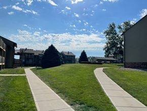Omaha apartment for rent - Residential buildings at Fox Run Apartments surrounded by open green space under a clear sky.