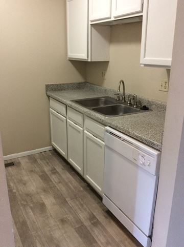 Olathe townhouse for rent - A kitchen with white cabinets and a granite countertop.