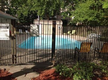 Omaha apartment for rent - A pool surrounded by a black fence with a sign on the left.