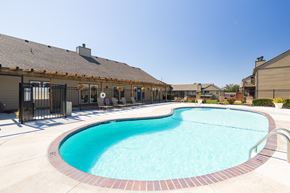 Overland Park townhouse for rent - A sparkling swimming pool at Cedar Crest Apartments, surrounded by lounge chairs and lush landscaping.