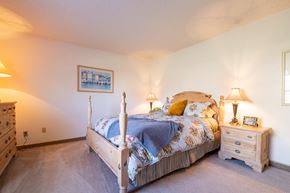 Overland Park townhouse for rent - A cozy bedroom in a two-bedroom unit at Cedar Crest Apartments, featuring a bed, side table, and drawer.