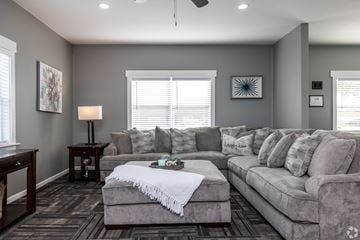 Olathe apartment for rent - A living room with a grey couch and a white throw blanket on it.