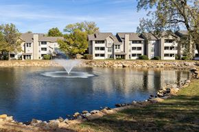 Overland Park apartment for rent - Three Lakes Apartments with a lake and fountain, surrounded by greenery and residential buildings.