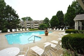 Overland Park apartment for rent - Outdoor swimming pool at Three Lakes Apartments, surrounded by lounge chairs and greenery.