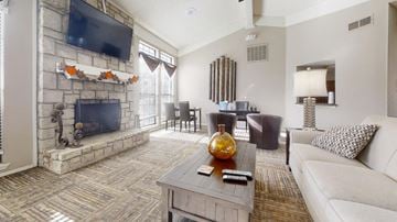 Overland Park apartment for rent - A living room with a stone fireplace and a television above it.