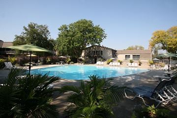 Omaha apartment for rent - A pool surrounded by trees and chairs.
